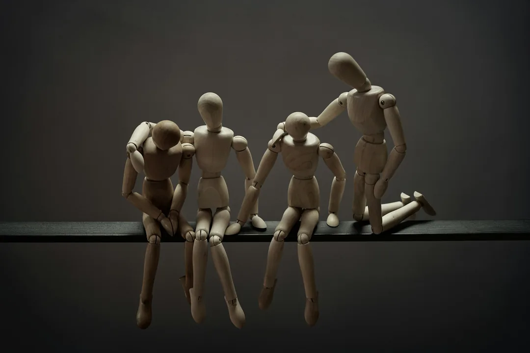 Cuatro maniquíes articulados de madera colocados sobre una tabla oscura, iluminados de forma lateral como en un plató de animación en volumen.